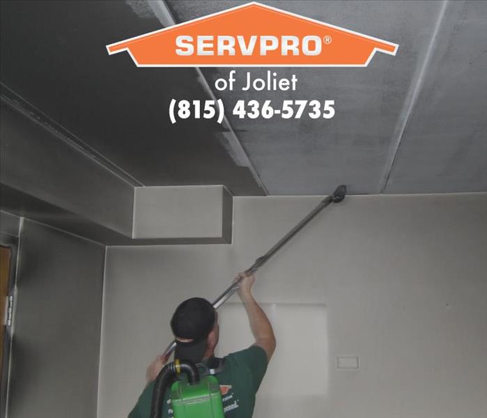 Team member cleaning wall and ceiling.