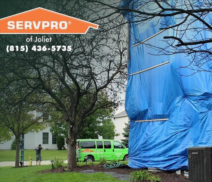 SERVPRO truck parked outside home with blue tarp.