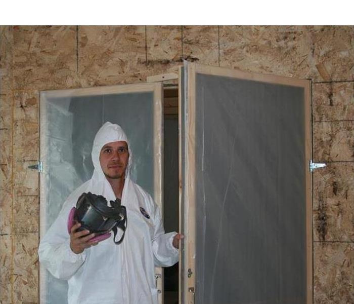 Technician holding a door, the door has plastic covers. Concept mold containment
